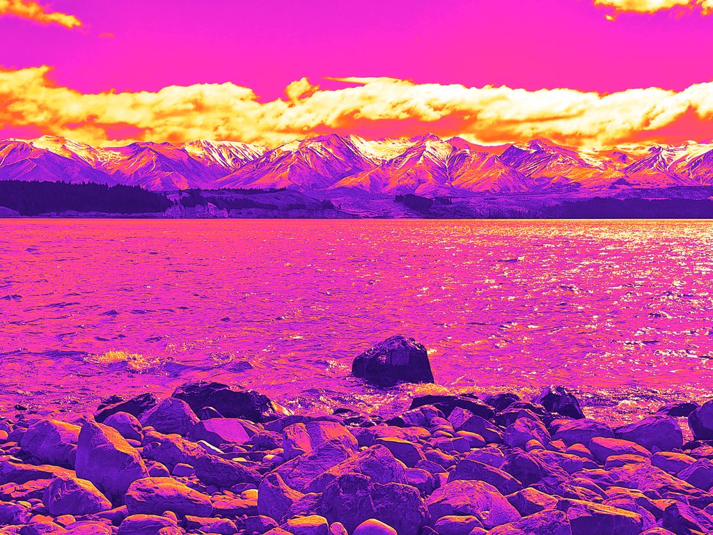 Rocks on a lake shore with a snowy range beyond, mapped to heat colours